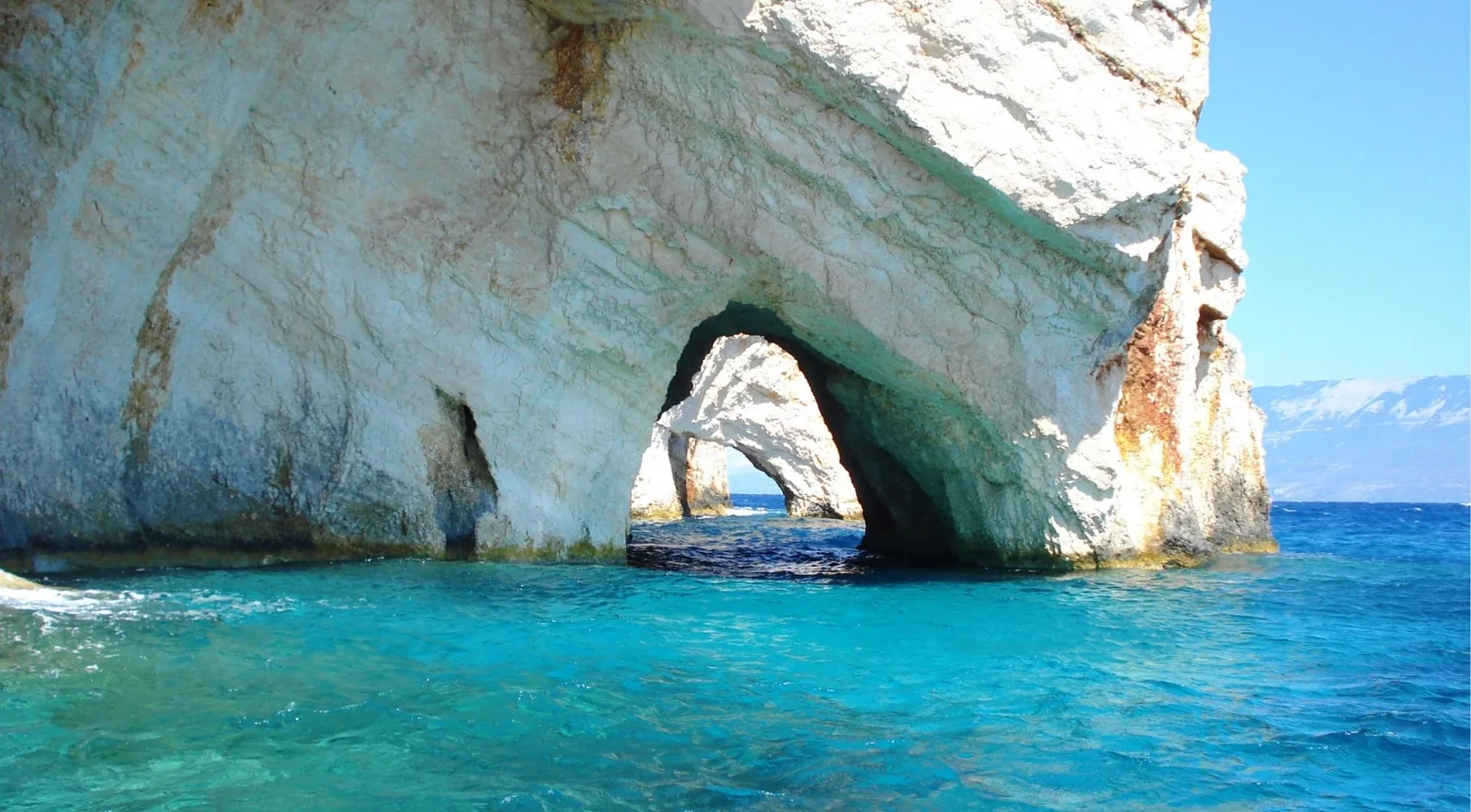 A natural limestone arch at the Blue Caves, the water beneath it lit an intense turquoise.